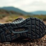 Close-up view of the sole of a Xero Shoes sneaker resting on a rocky dirt path, with blurred mountains and greenery in the background. The tread pattern and XERO branding highlight the durability and 5,000-Mile Sole Warranty.