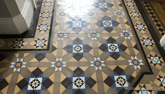 Victorian hallway tiles with dished traffic wear and dull clay surface in walking paths
